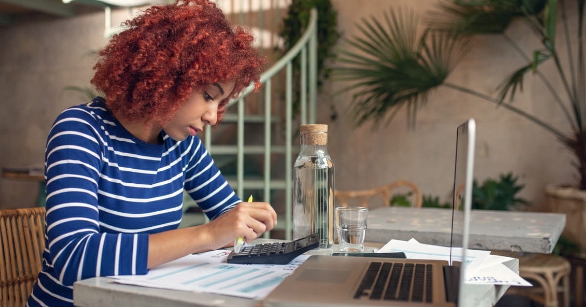 Empreendedora confere limite faturamento enquanto faz cálculos