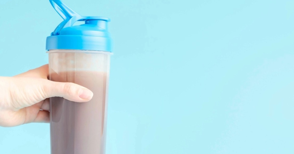 Mão segurando coqueteleira com Whey Protein representando como montar loja de suplementos